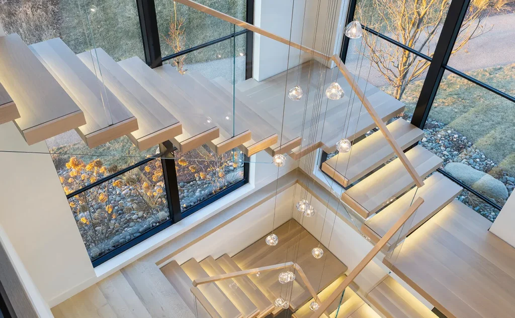 Floating staircase with glass balustrade beside large window